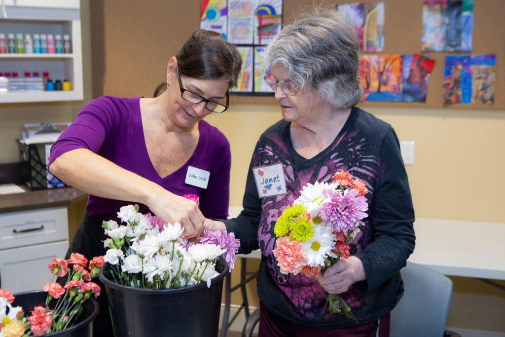 Woman and aide working on a flower arrangement