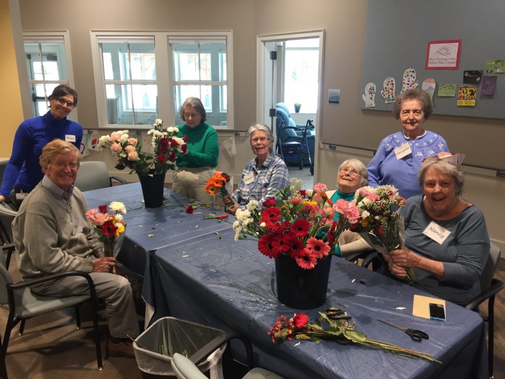 Group sitting around a table creating floral arrangements