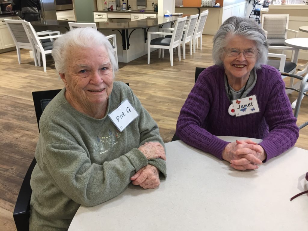 Two seniors sitting at a table in the common room